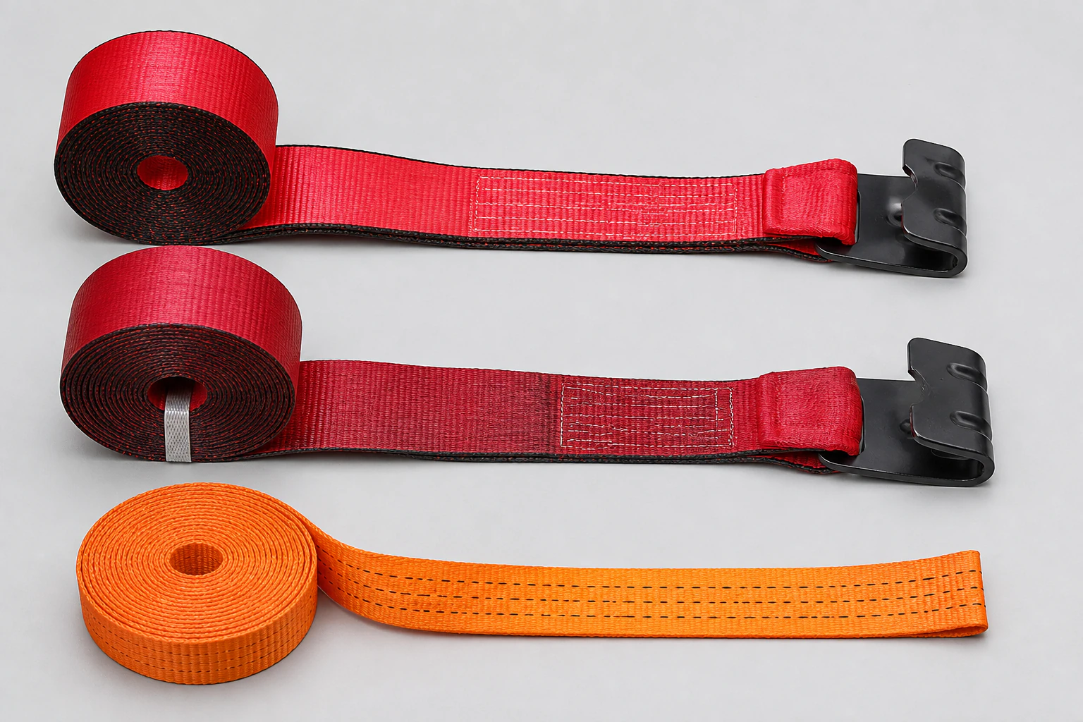 Two complete red flat-hook winch straps and one orange woven webbing coil arranged in separate selection lanes