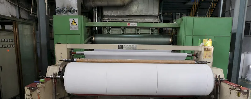 White nonwoven material roll at a production machine with the sheet surface and roll route visible