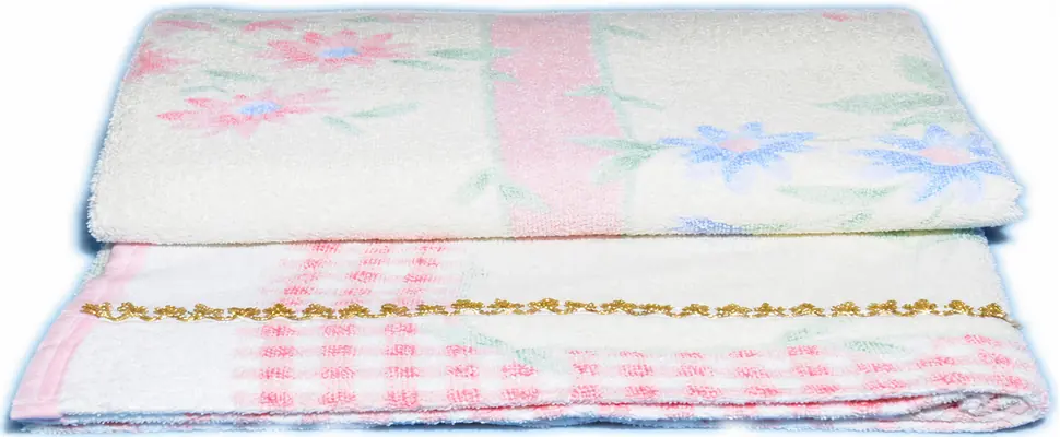 Two complete white patterned towels showing folded edges and gold decorative trim